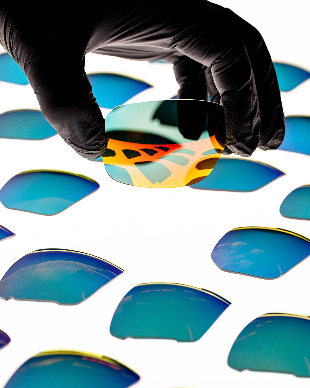 picking up a pair of red replacement lenses off a table with other lenses in the background